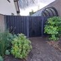 Tuinscherm garderen zwart grenen in combinatie met een zwarte tuindeur en grijze betonpalen. 